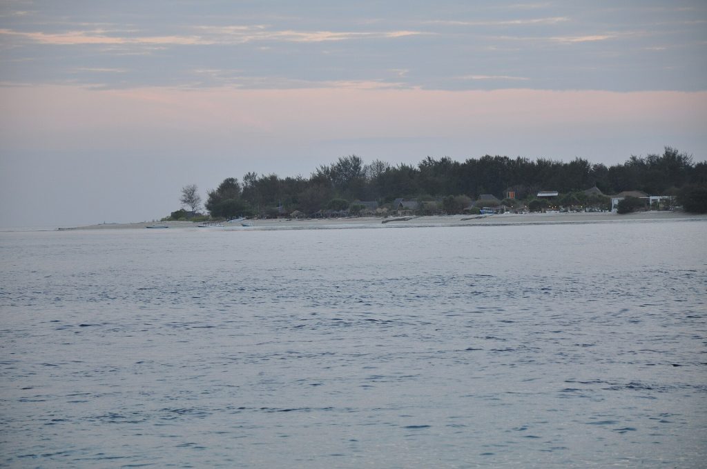 L'île de Gili Meno vue depuis la mer, avec sa plage et ses bateaux à l'ancre.